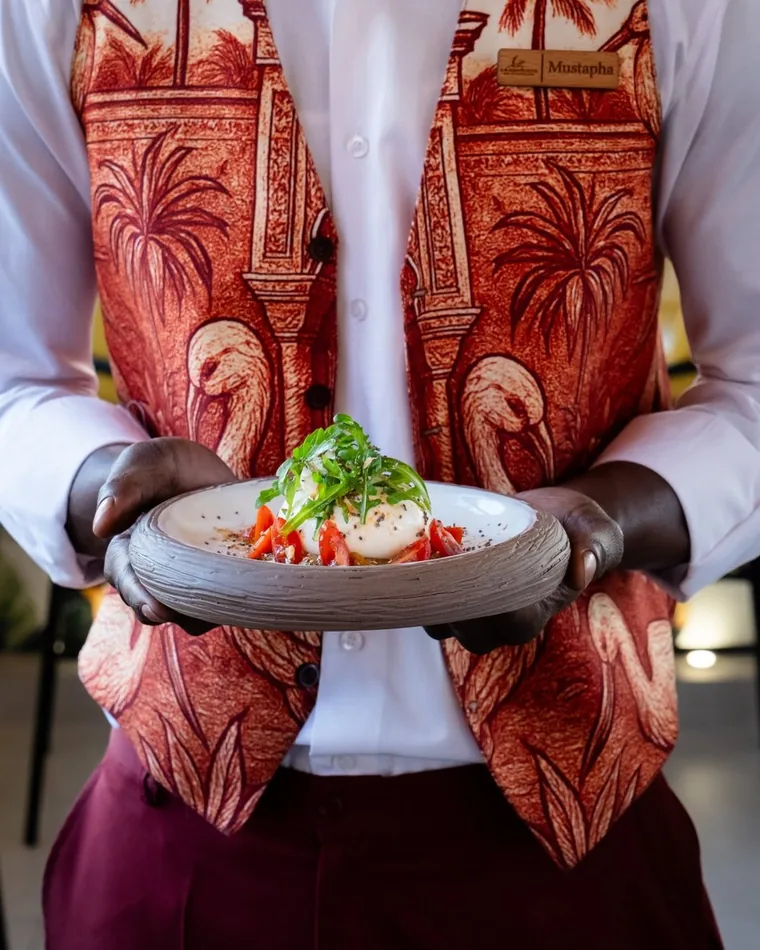 Waiter serving a burrata plate at La Kamounya
